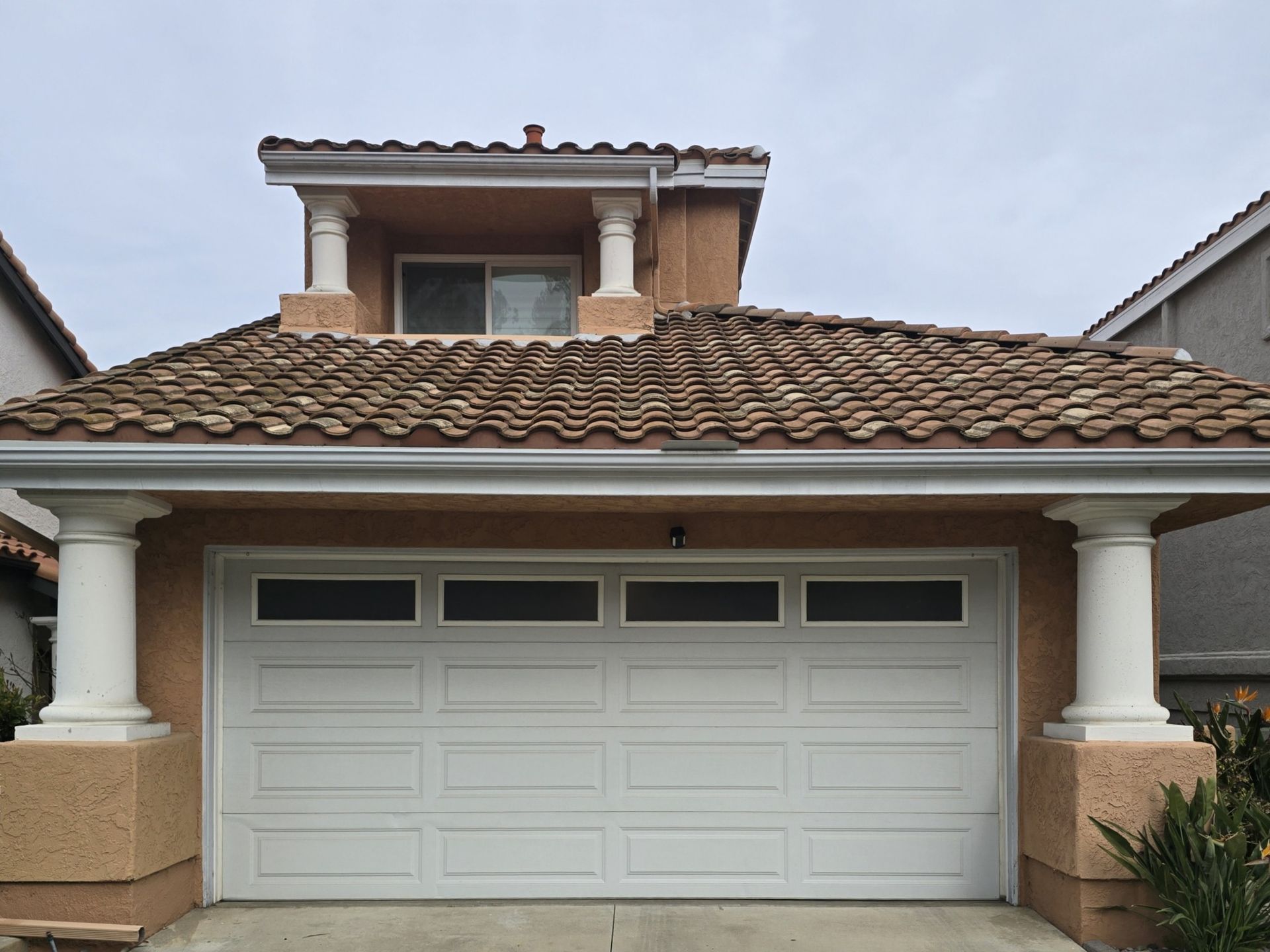 Suburban house with double garage and tiled roof under an overcast sky