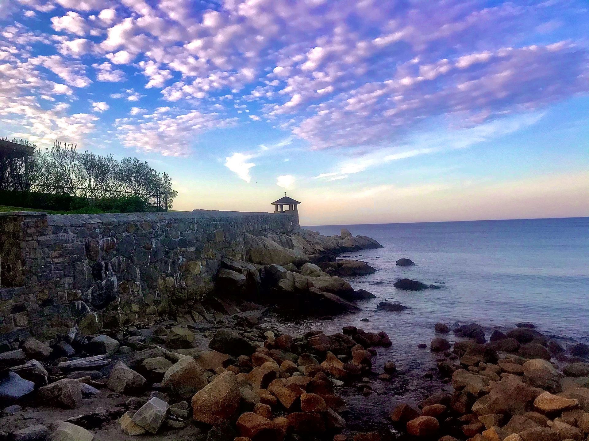 A stone wall surrounds a body of water with a purple sky in the background.