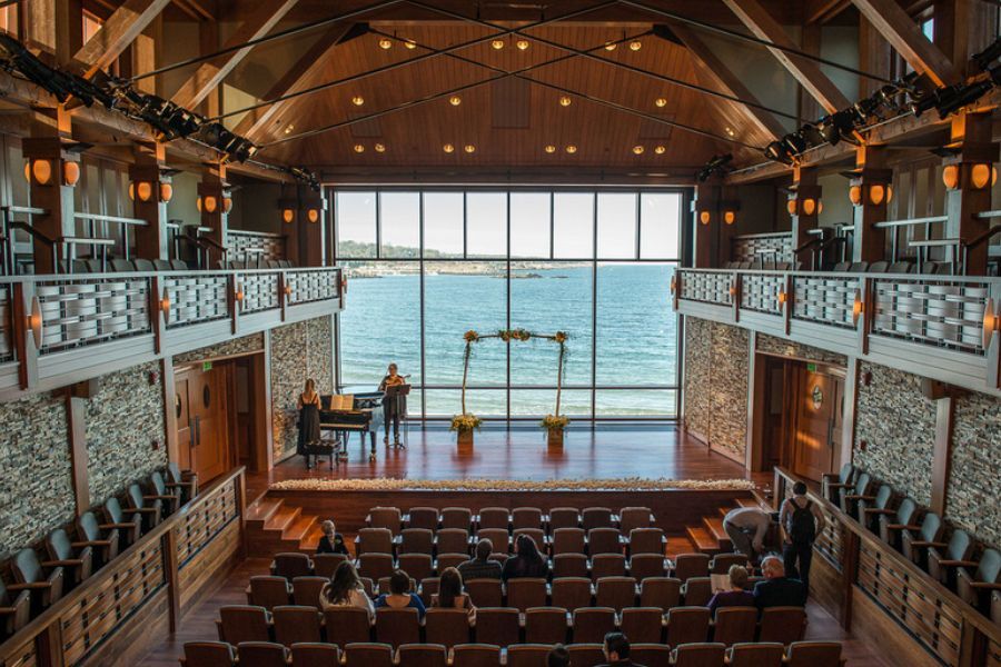 A large auditorium with a large window overlooking the ocean.