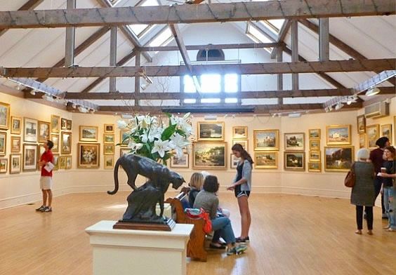 A group of people are looking at a statue of a panther in a museum.