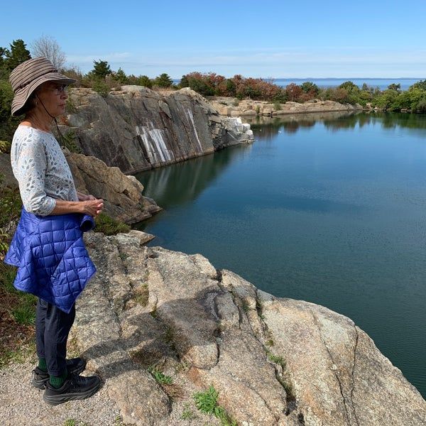 A woman is standing on a rock overlooking a body of water.