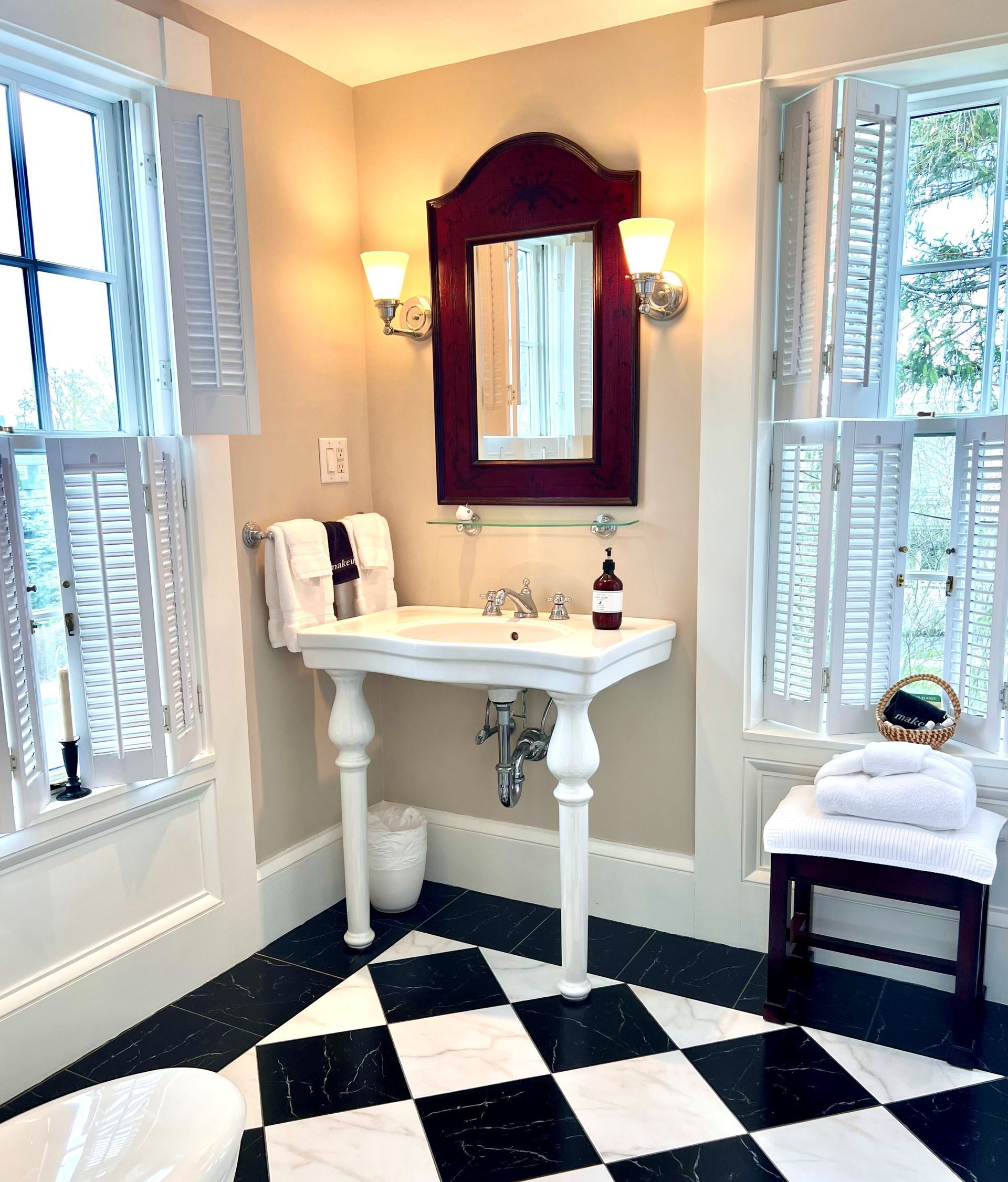 A bathroom with a sink , mirror , and checkered floor.