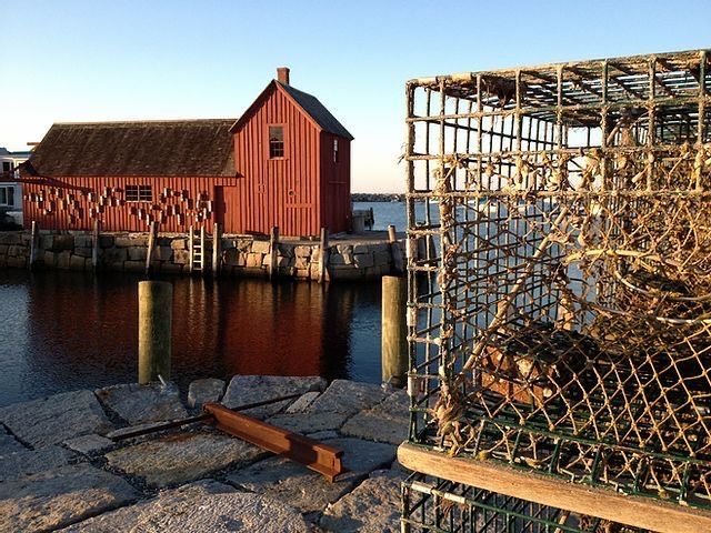 A crab cage sits in front of a red barn