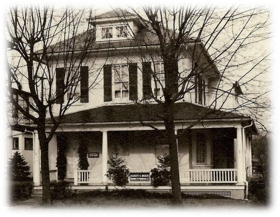 A black and white photo of a man and woman standing on a porch
