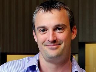 A person with short hair and a light blue striped shirt smiling gently at the camera.