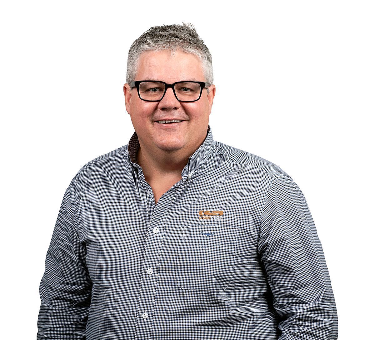 A person with short, light-colored hair and glasses wearing a black and white checkered button-down shirt.