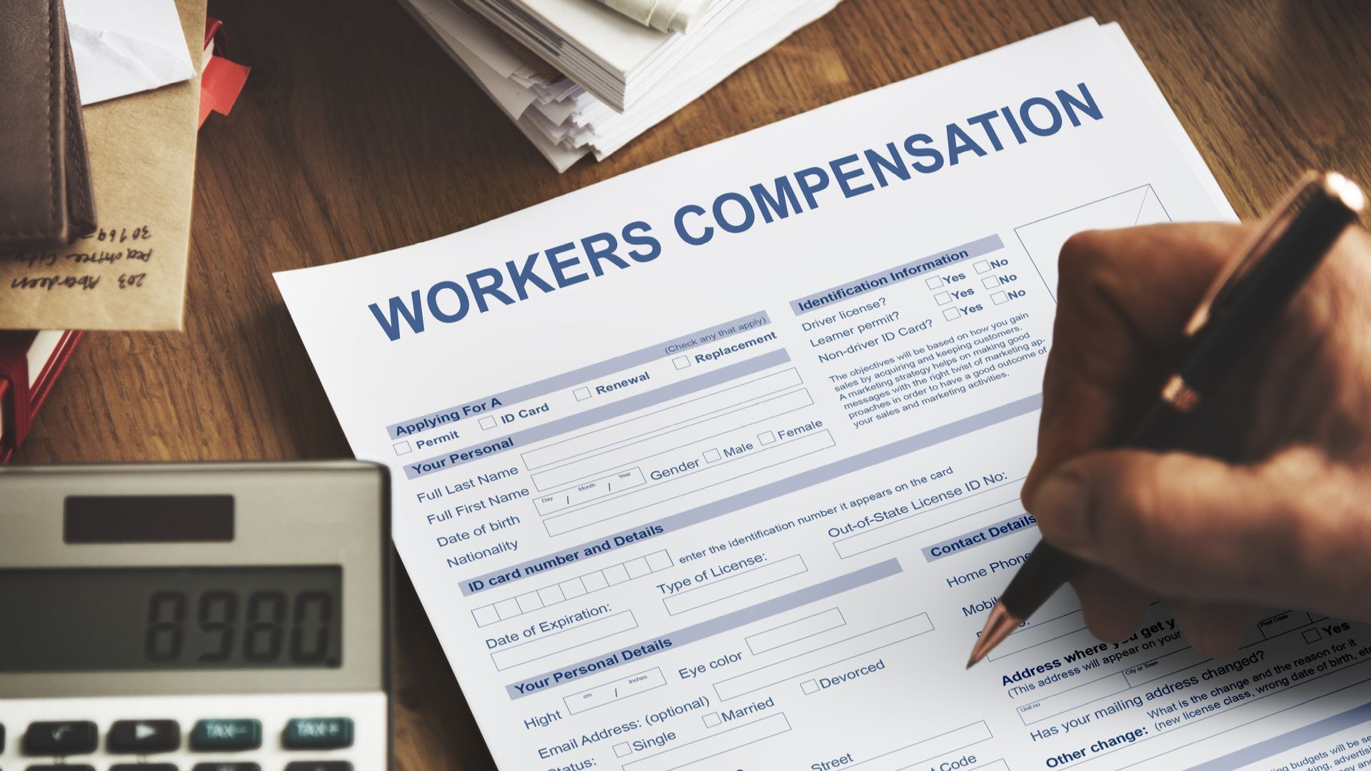 a person is filling out a workers compensation form next to a calculator .