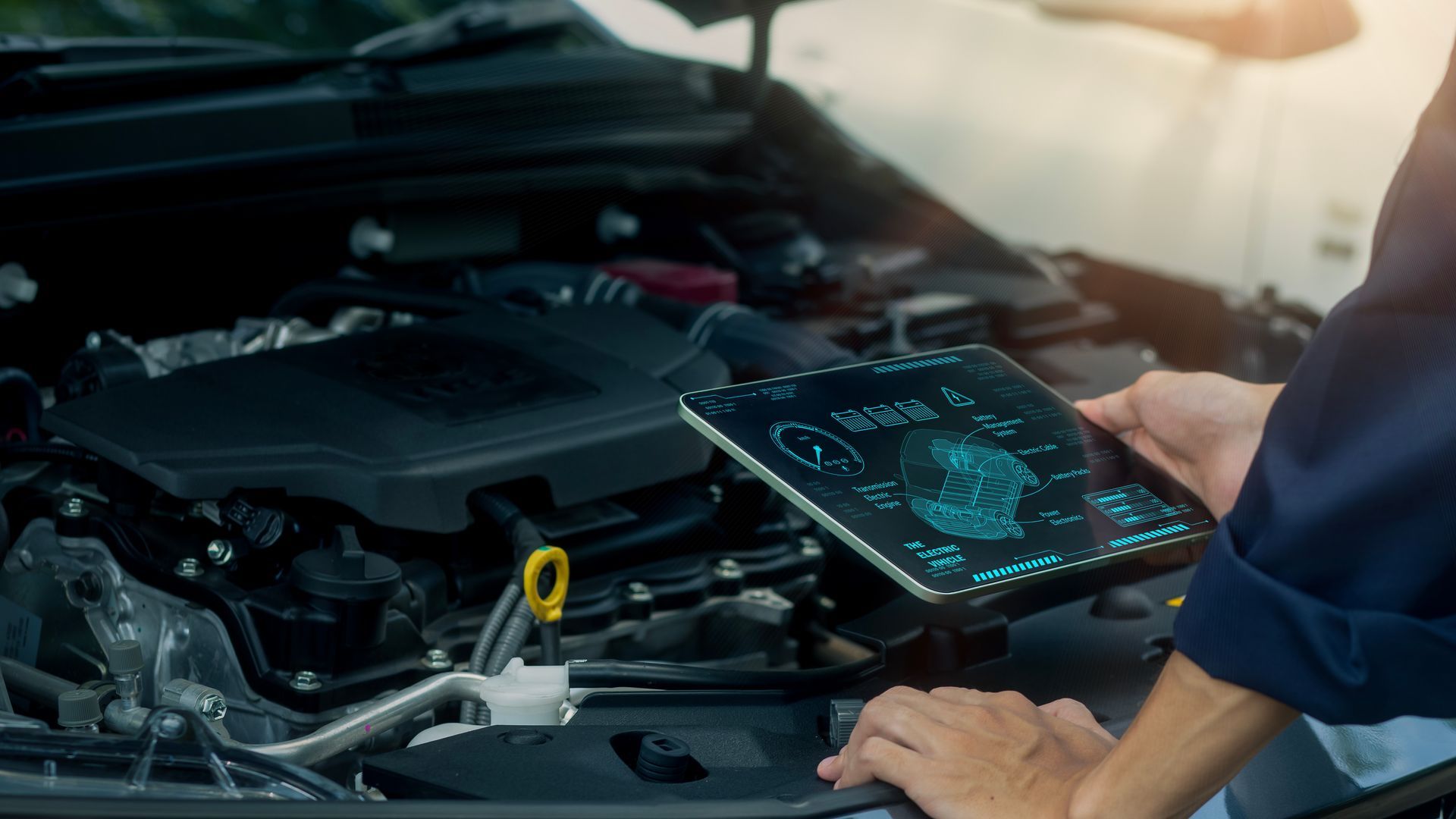 Mechanic using a tablet to diagnose a car engine, outdoors.
