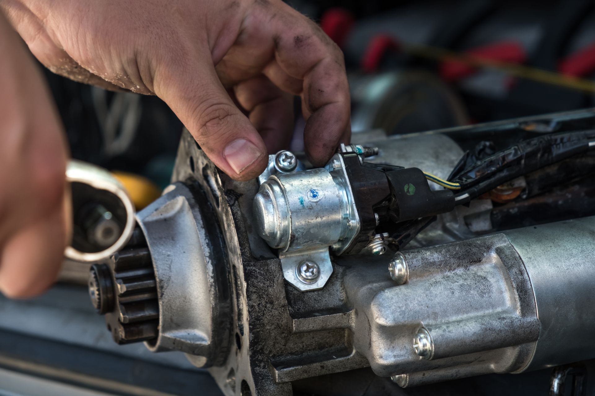 A person's hands installing a part on an automotive starter motor.