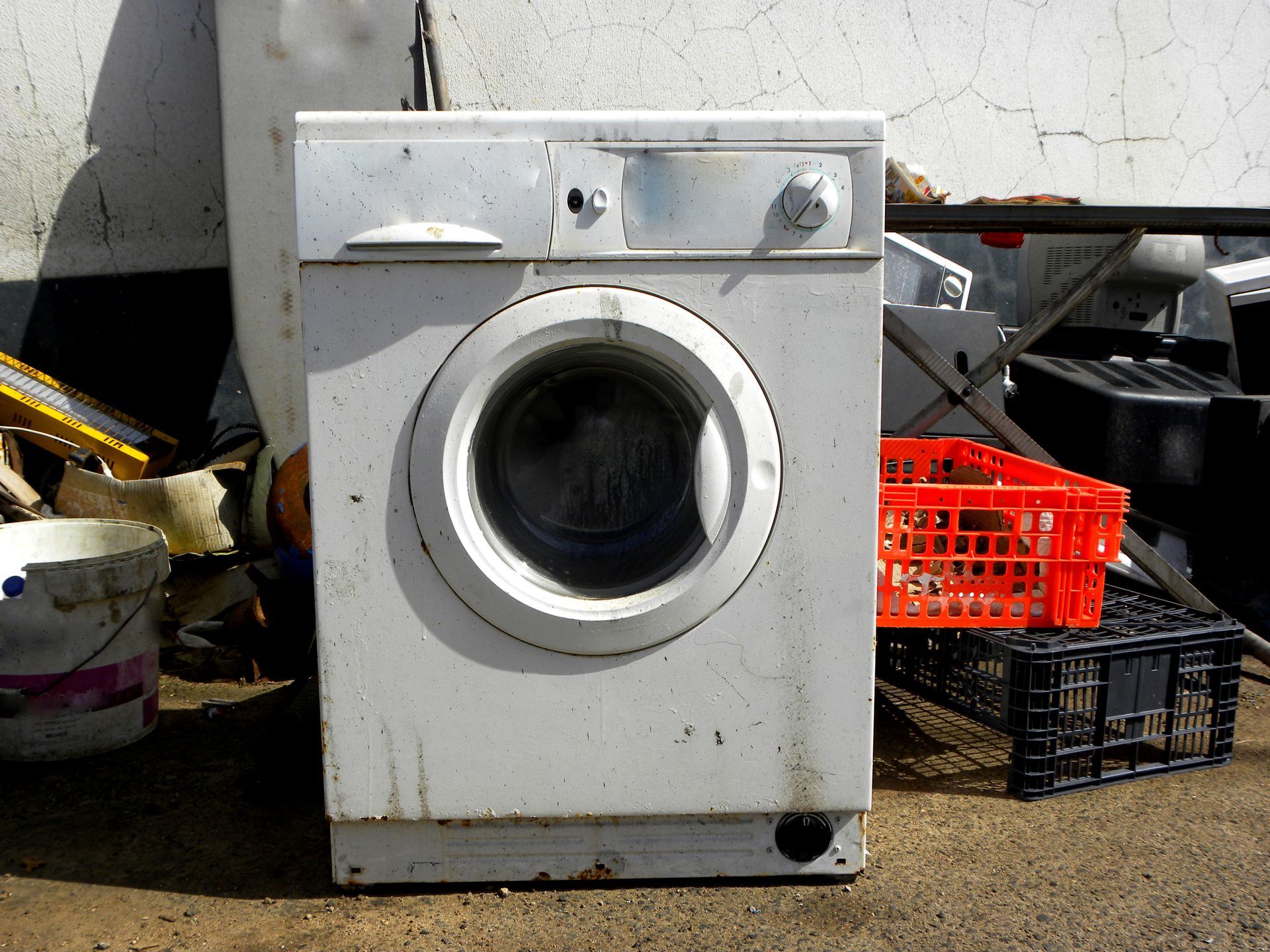 White washing machine outdoors, near an orange crate.