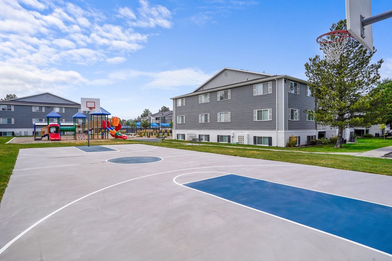 Outdoor community playground and basketball court with apartment buildings in the background.  Discover modern townhomes in Millcreek, UT by scheduling a tour at Turnberry Apartments today.

