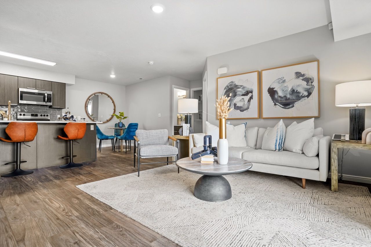 Open-concept living room with a beige sofa, round coffee table, and kitchen island with orange bar stools.