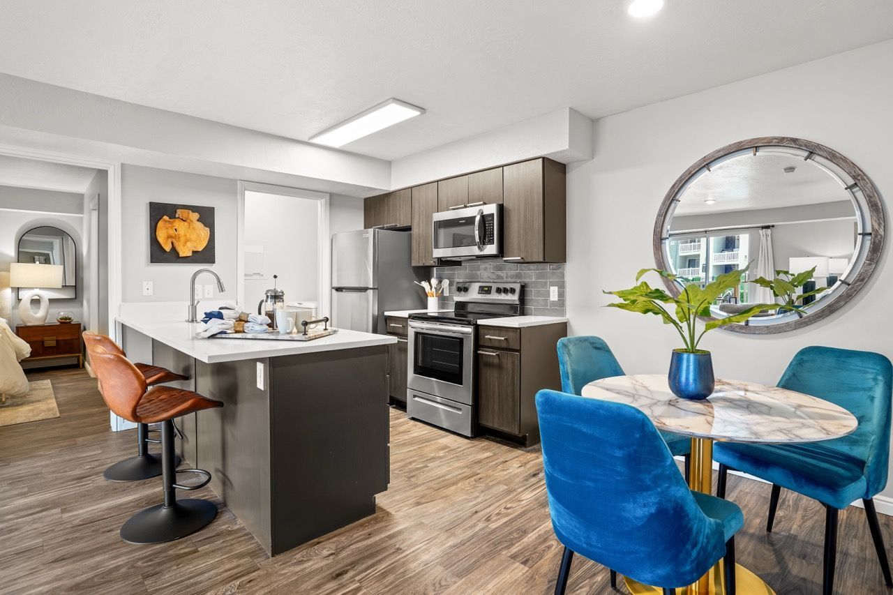 Open-concept kitchen with island, stainless steel appliances, and a round marble dining table.  See why residents enjoy our community by touring Turnberry Apartments and exploring nearby Millcreek apartments for rent options.