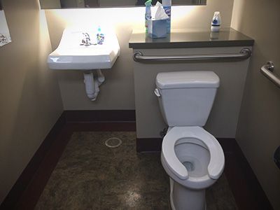 A bathroom with a toilet , sink and mirror.