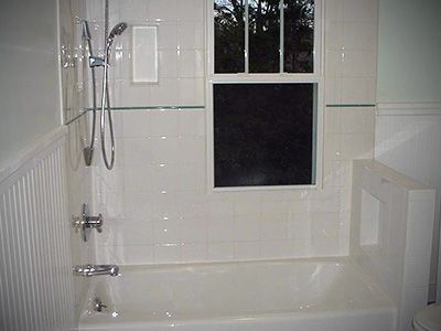 A bathroom with a tub , shower , toilet and window.