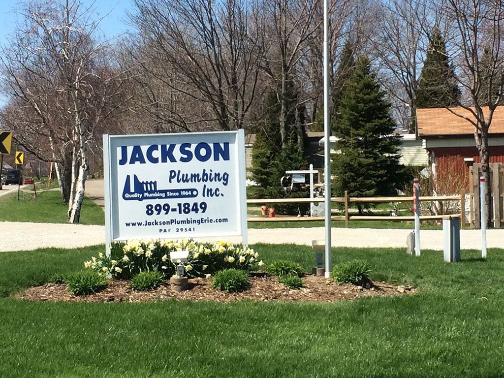 A sign for jackson plumbing inc. is in the grass