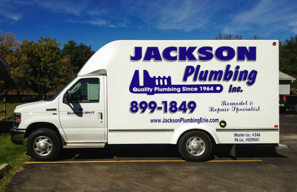 A white jackson plumbing truck is parked in a parking lot