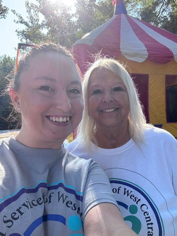 Two women smiling, posing for a selfie in front of a colorful inflatable structure.