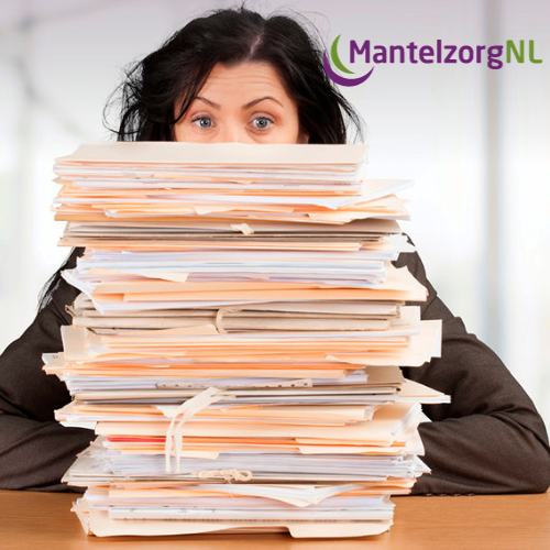 Vrouw kijkt over een hoge stapel dossiers heen en ziet er overweldigd uit; kantooromgeving.