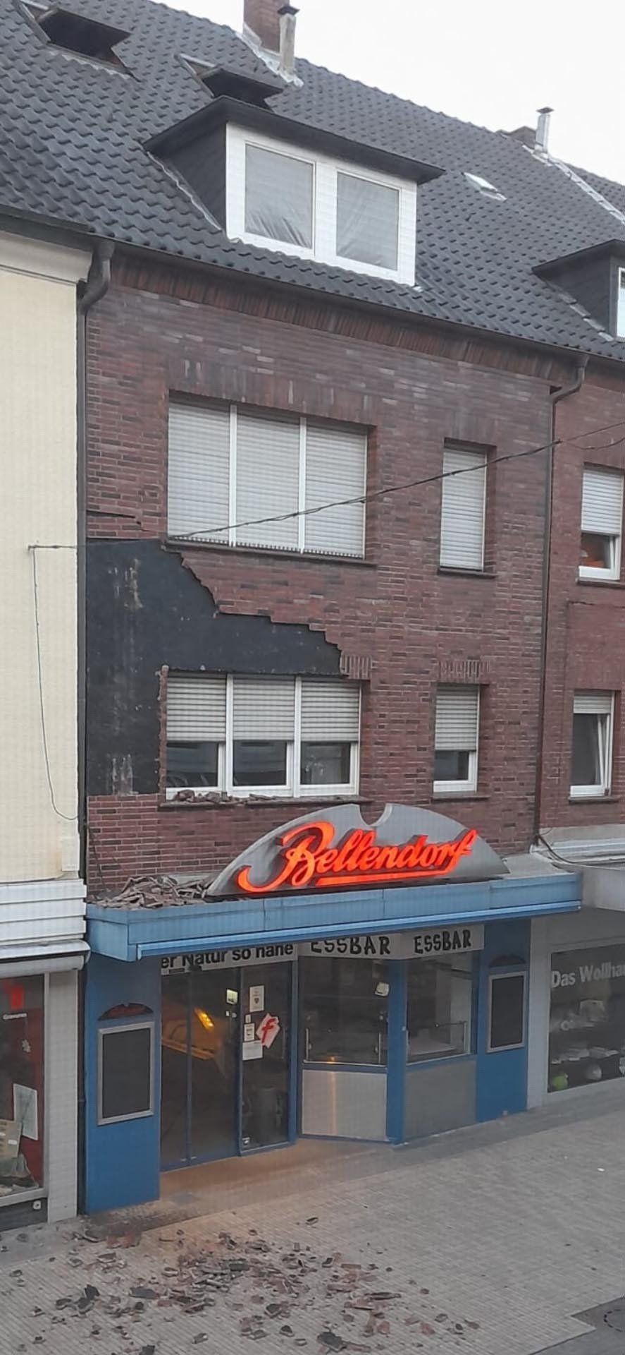 Außenansicht eines Backsteingebäudes mit verbrannter Fassade. Darunter befindet sich das Restaurant „Hollywood“.