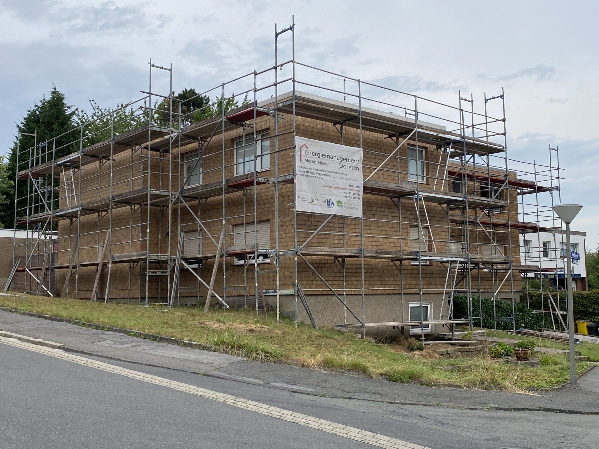 Gebäude im Umbau mit Gerüst. Backsteinfassade, bewölkter Himmel.