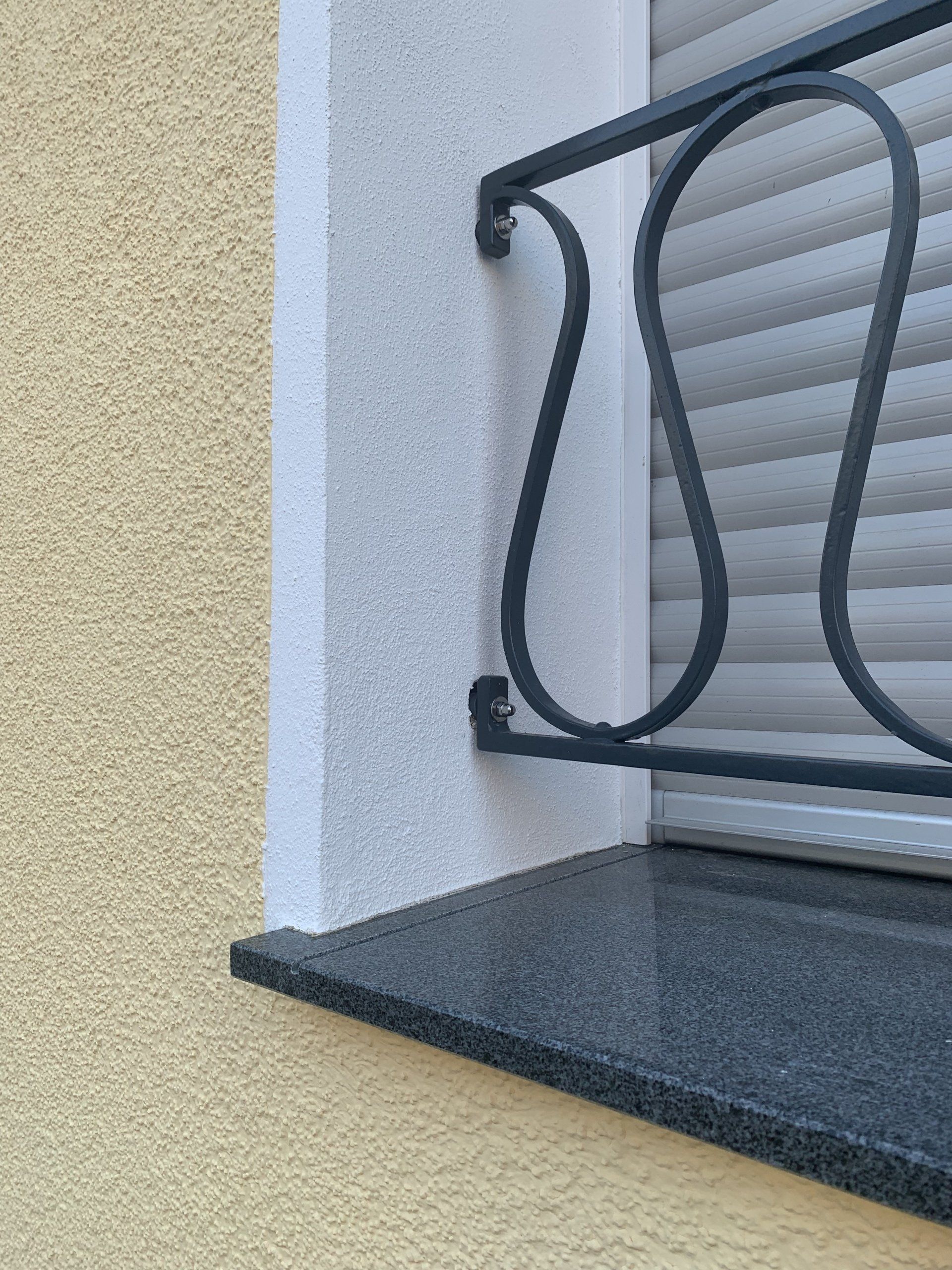 Nahaufnahme eines Fensters mit einem schwarzen dekorativen Geländer. 