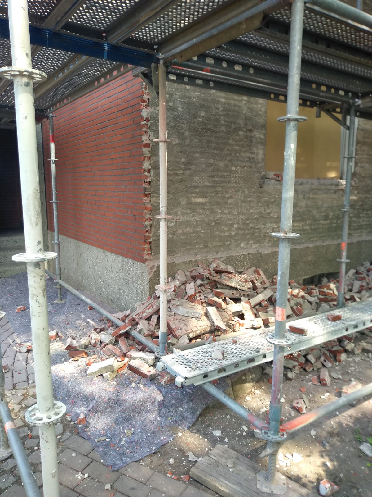 Backsteingebäude im Bau, rote und graue Ziegel sichtbar, Gerüst vorhanden.