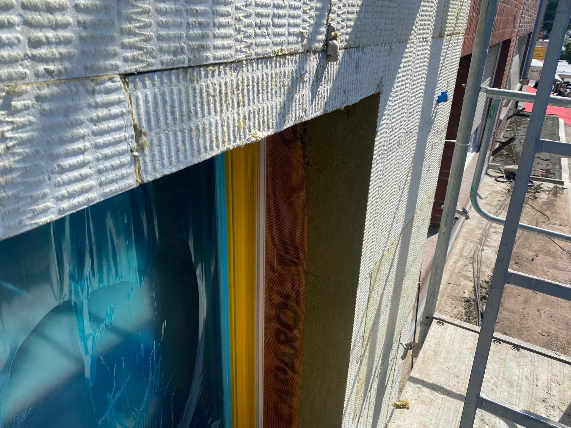 Außenwandkonstruktion: Isolierung, Schutzhülle, Gerüst, blaue und gelbe Elemente.