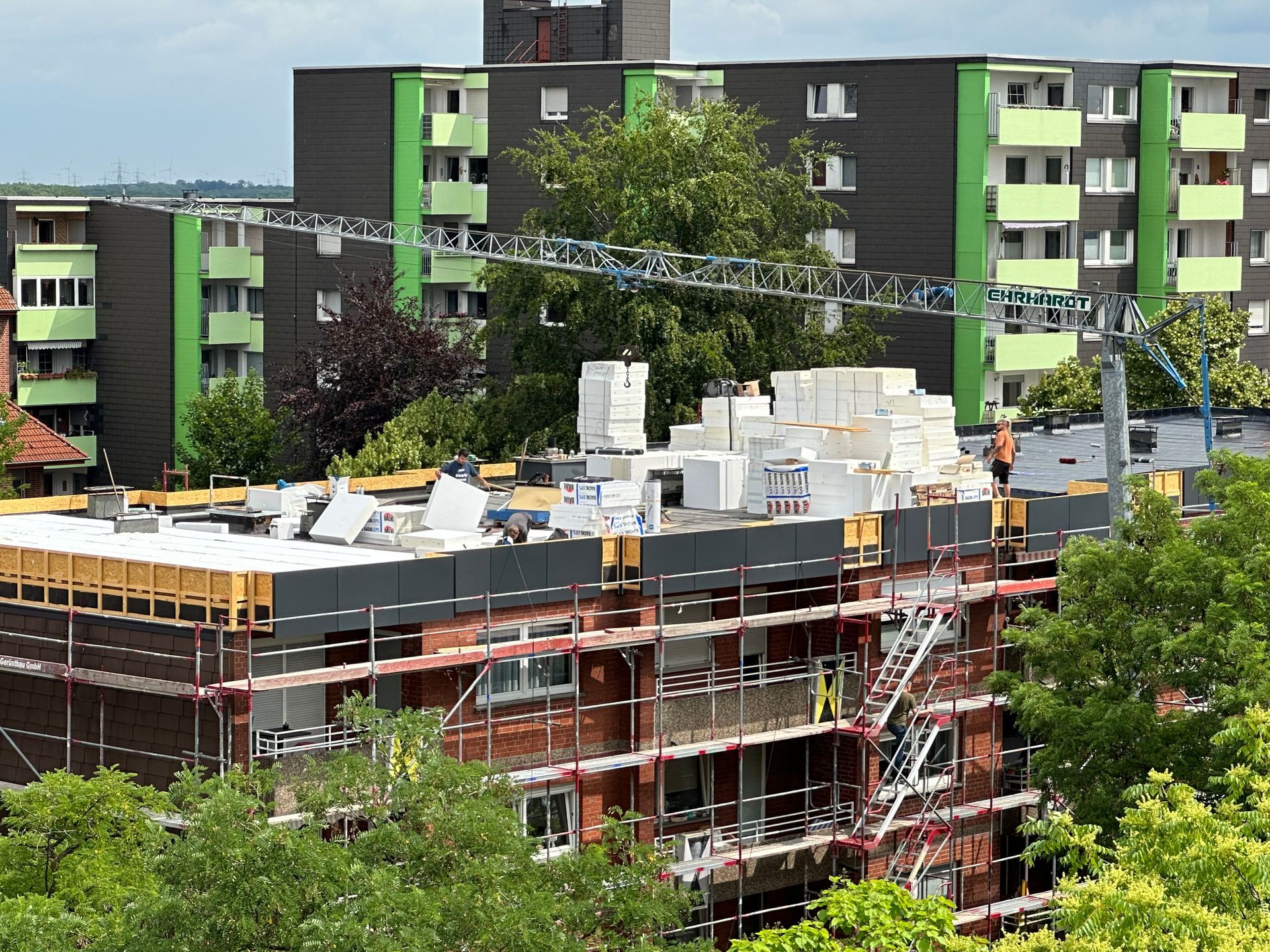 Baustelle mit Kran, Arbeitern und Wohnhäusern.