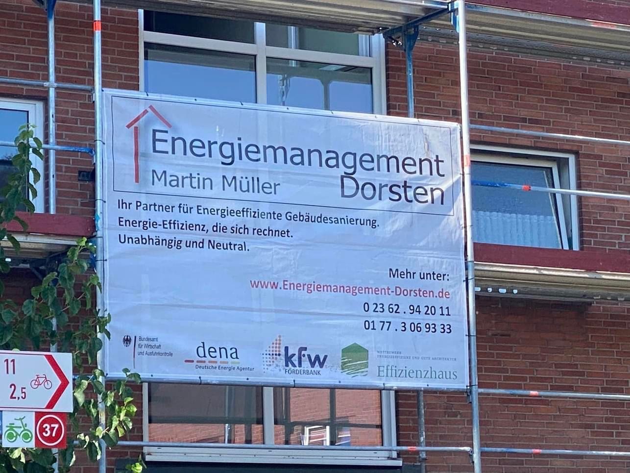 Banner am Gebäude: „Energiemanagement Dorsten“ mit Kontaktdaten, Gerüst sichtbar.