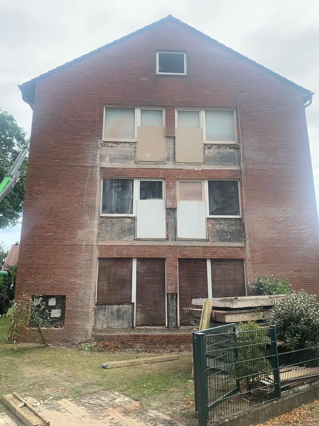 Rotes Backsteingebäude mit vernagelten Fenstern, Abrissspuren.