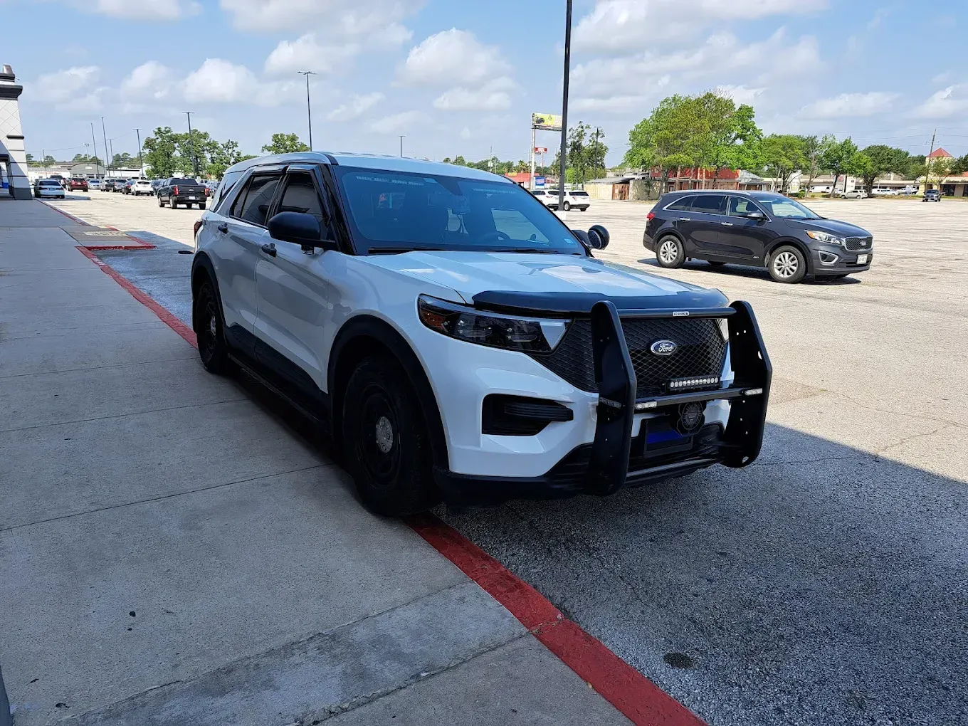 A white police car is parked in a parking lot.