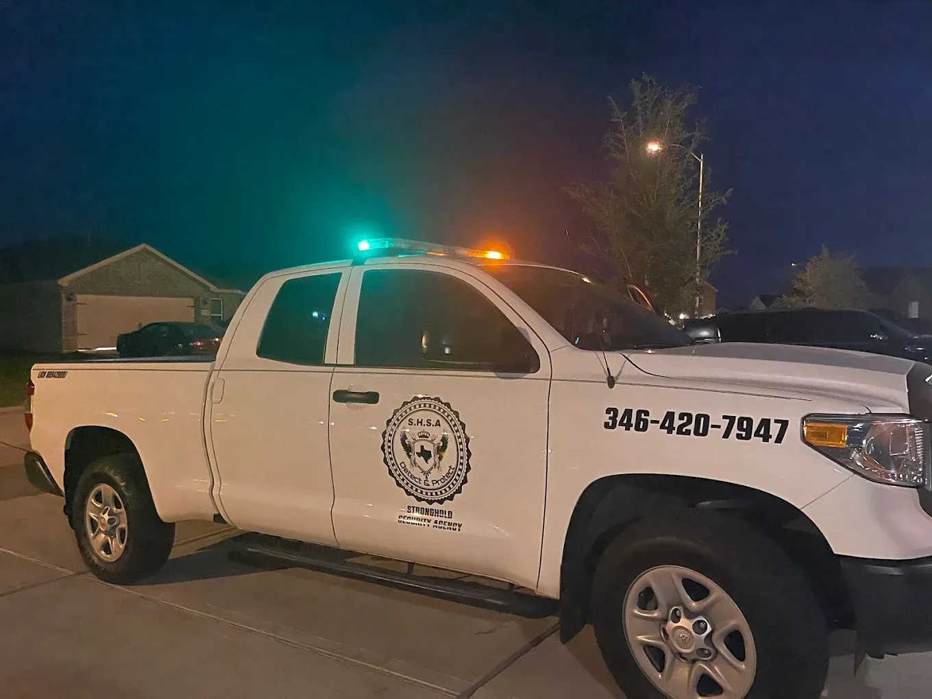 A white truck is parked on the side of the road at night.