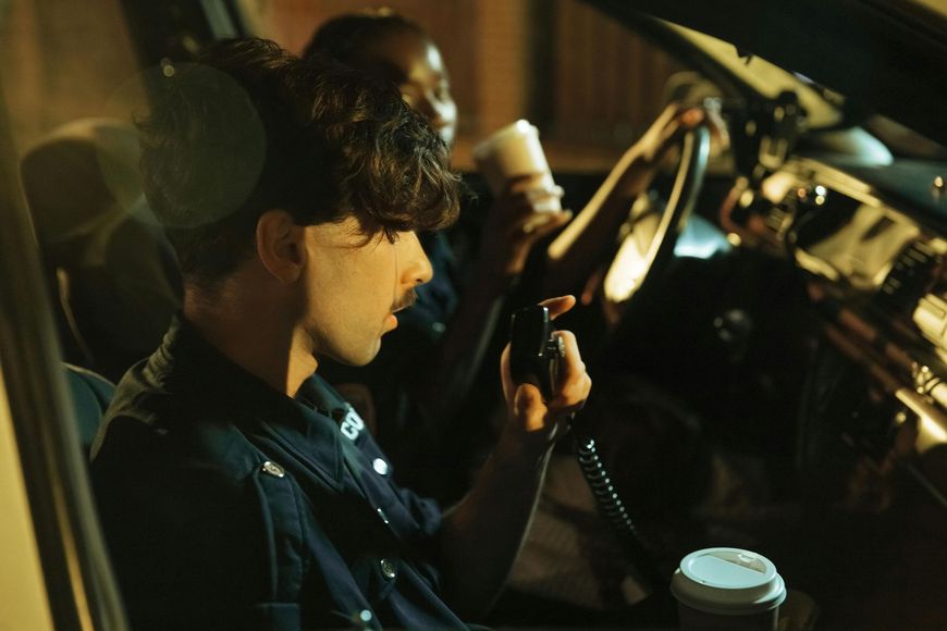 A police officer is talking on a walkie talkie in a car.