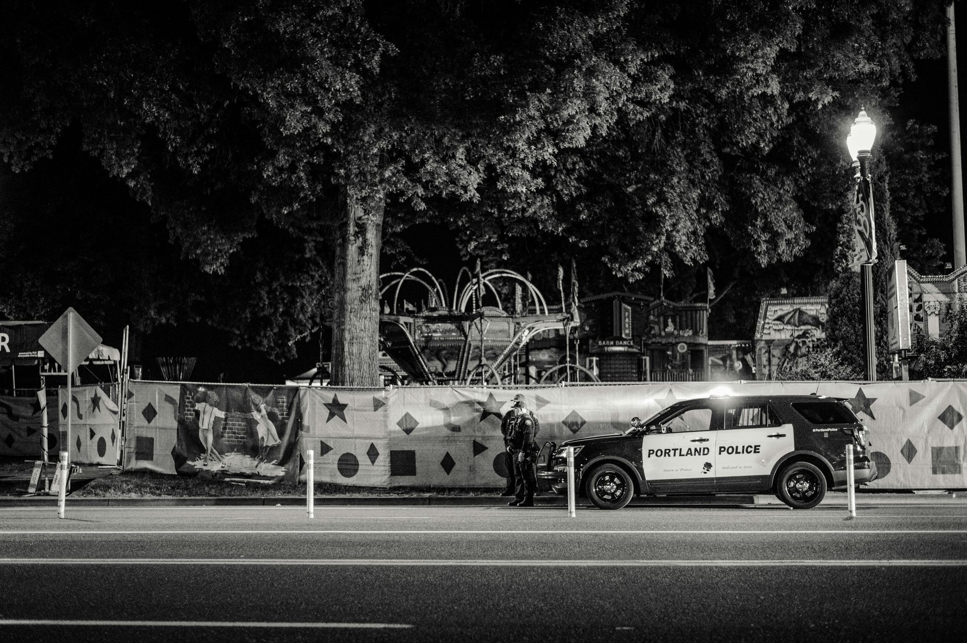 A black and white photo of a police car parked on the side of the road.