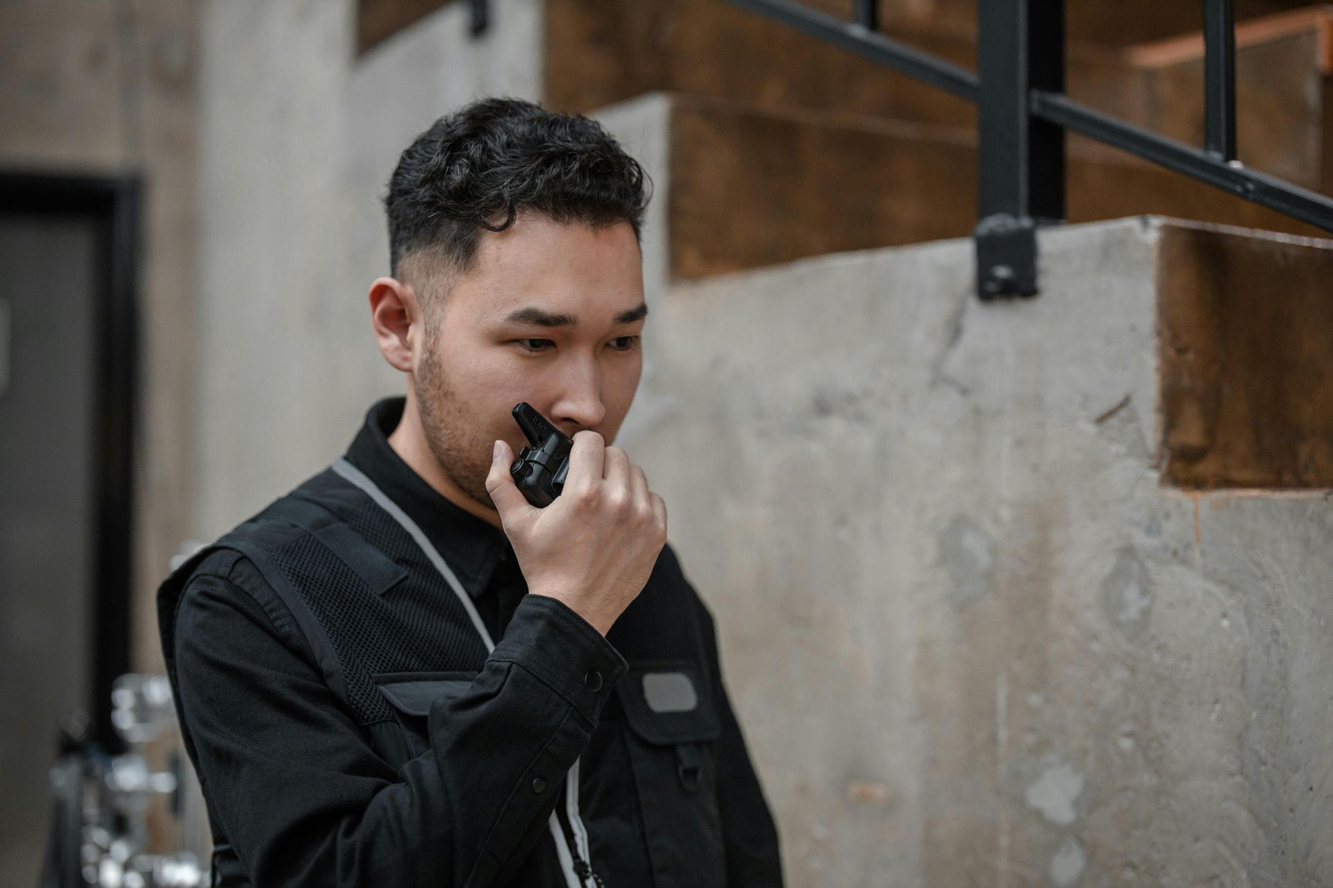 A man in a black jacket is talking on a walkie talkie.