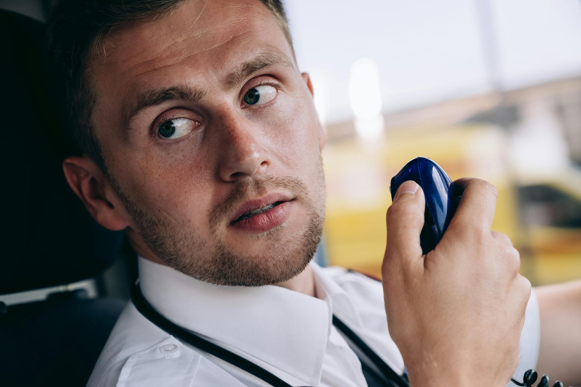 A man is sitting in a car talking on a walkie talkie.