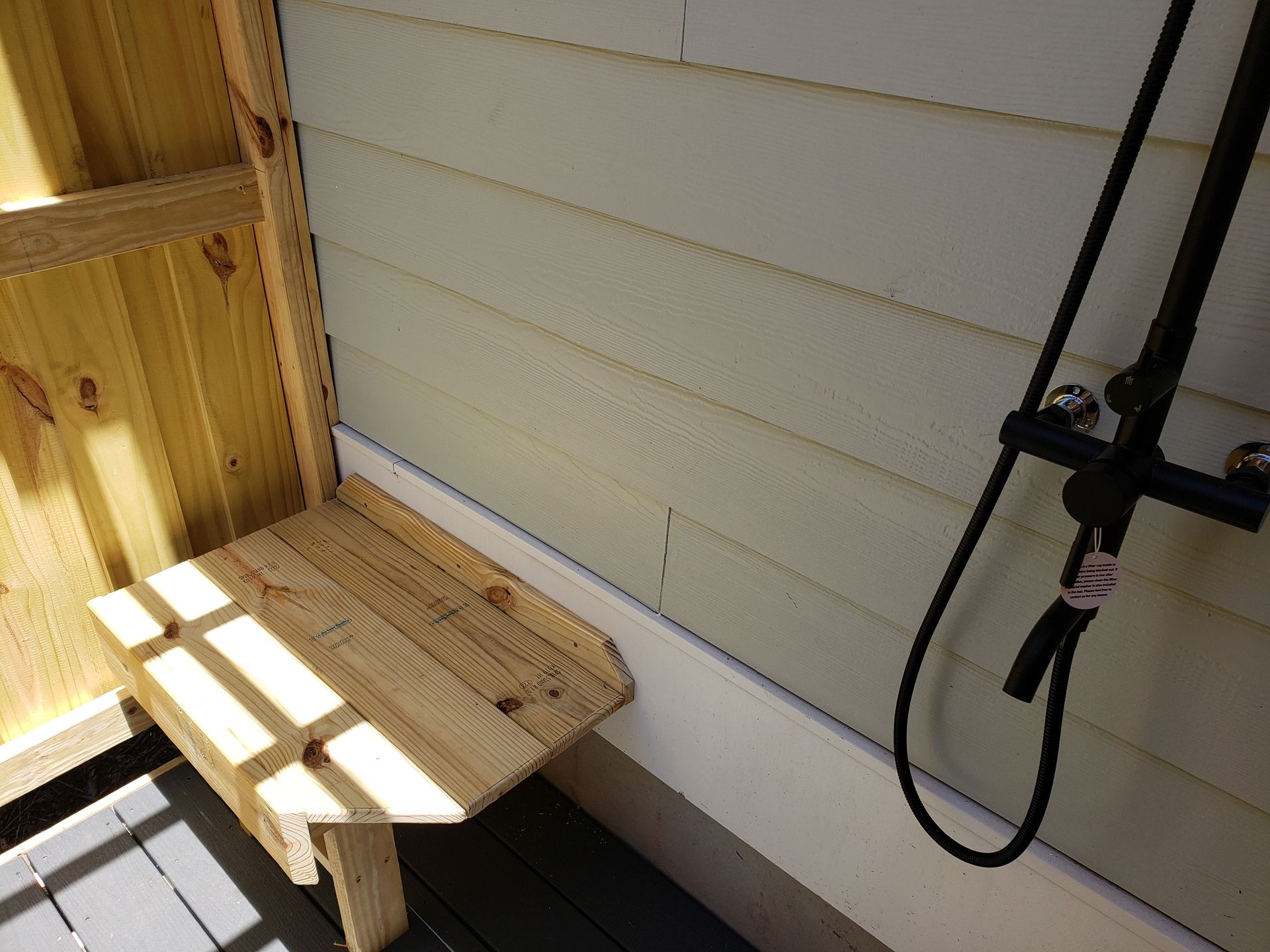 Wooden shower bench attached to the wall with shower fixtures visible.