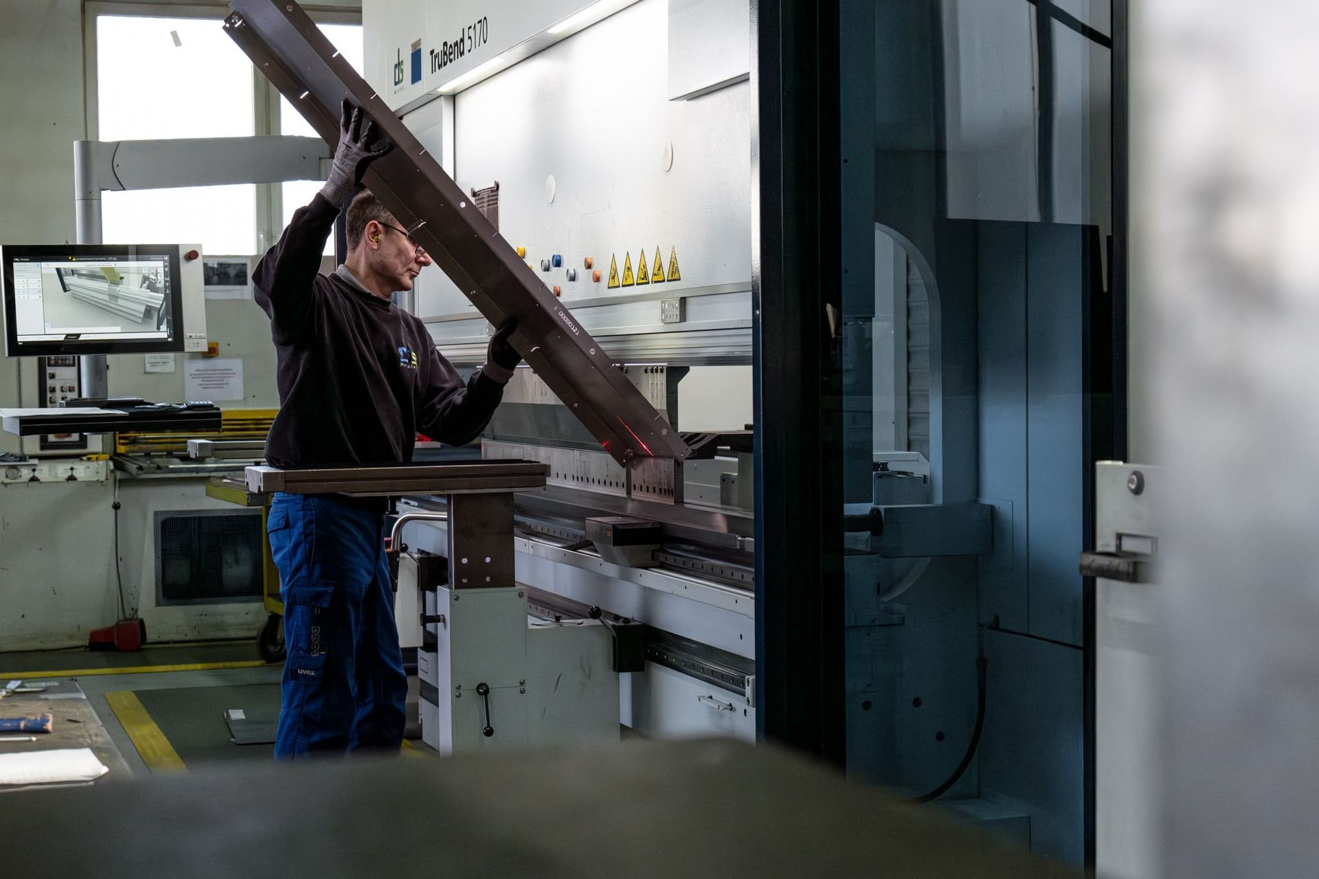 Ein Arbeiter bedient eine große Metallmaschine in einer Industriewerkstatt.