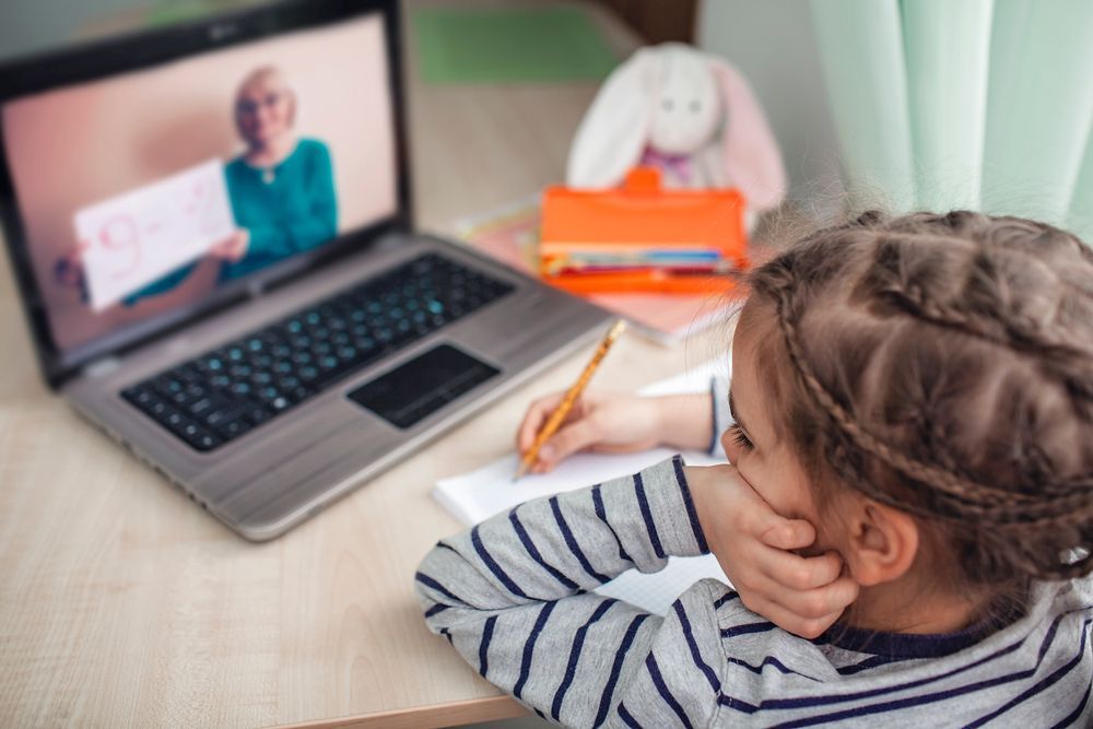 Child Watches Online Lesson on Laptop, Writing in Notebook. Teacher Appears on Screen — RIP IT UP Reading in Maitland, NSW
