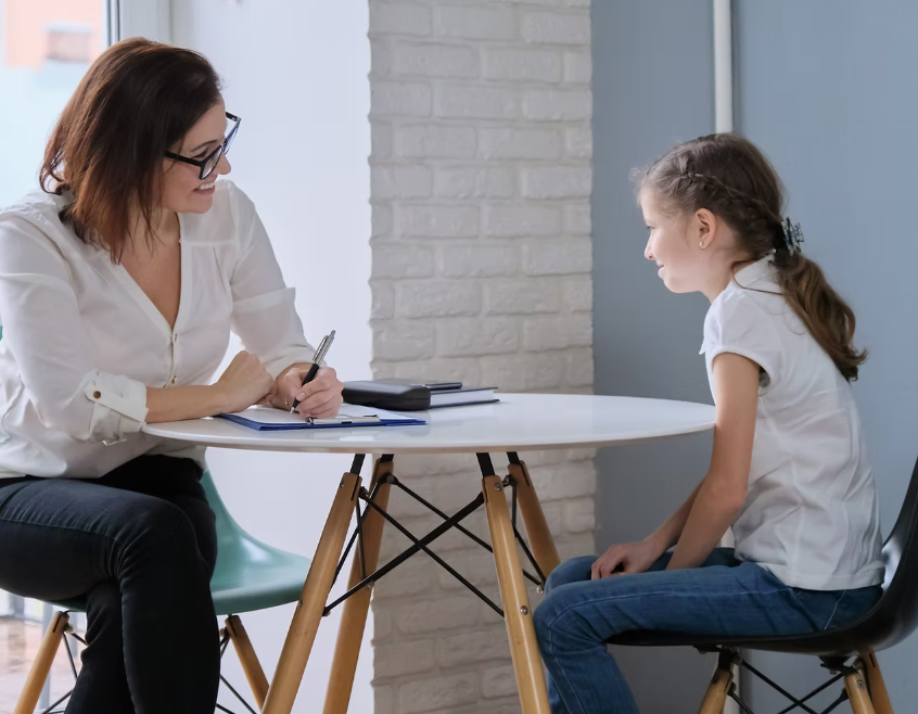 A woman is sitting at a table talking to a young girl. - RIP IT UP Reading in Maitland, NSW