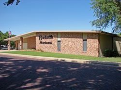 Buckworth Montgomery funeral home, brick building, sign, American flag, sunny day.