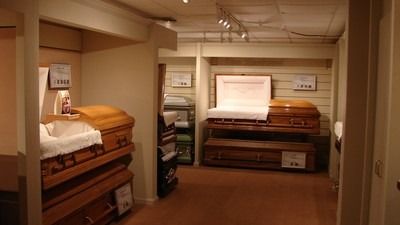 Interior of a funeral home displaying several closed and open caskets on display shelves.