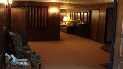 Dark, wood-paneled room with carpet and furniture; two open doorways lead to more rooms.