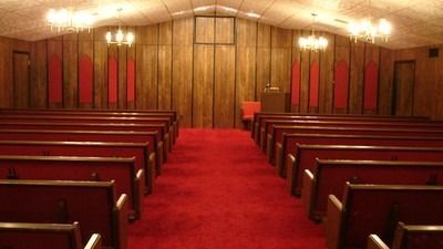 Interior of a church sanctuary with red carpet, wooden pews, and pulpit.