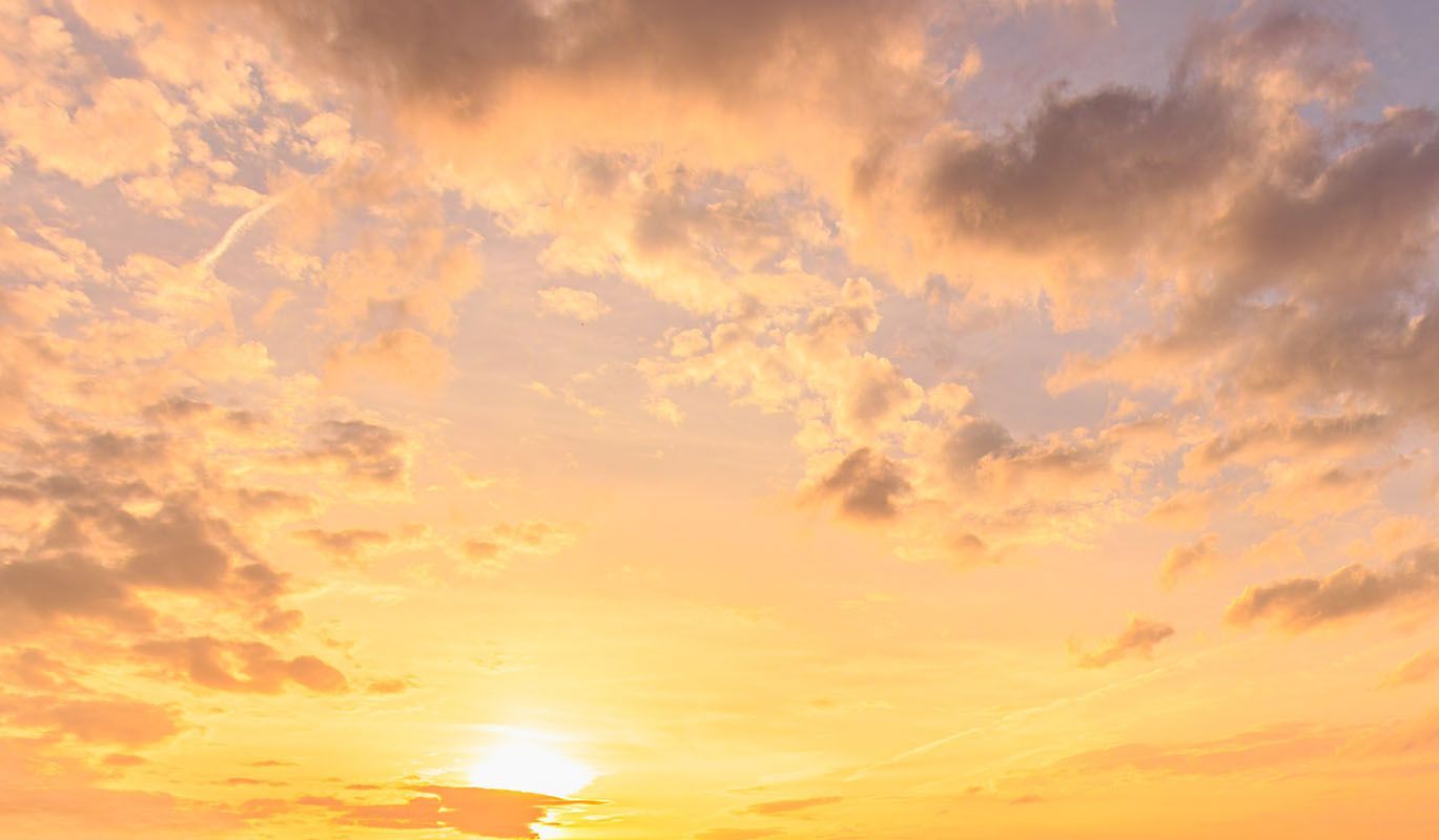 Sunset sky with yellow, orange, and gray clouds.