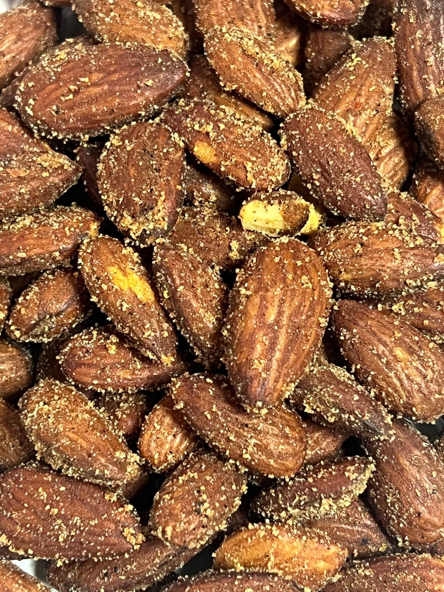 A close up of a pile of roasted almonds on a table.