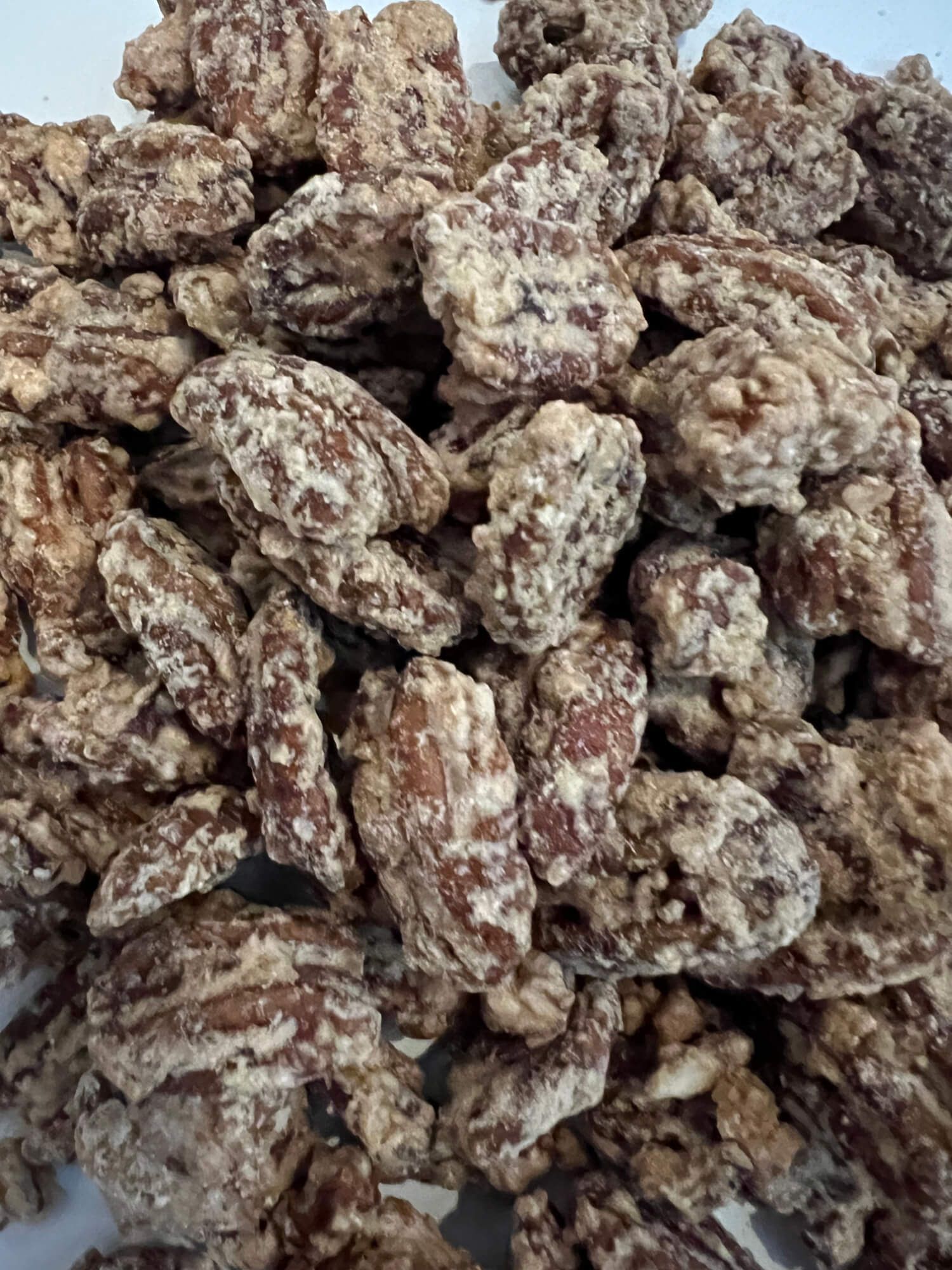 A pile of candied pecans on a white plate.