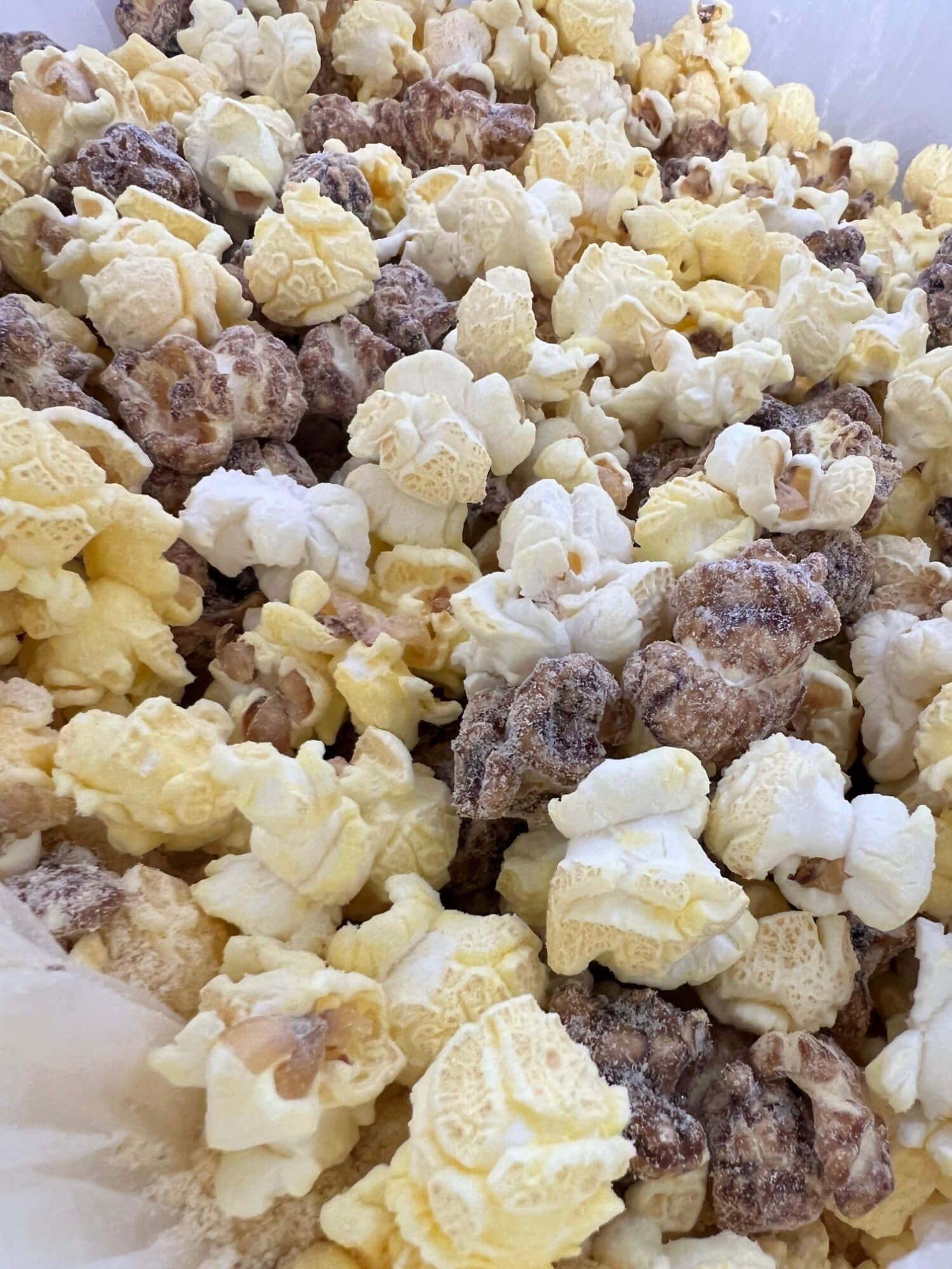 A close up of a pile of popcorn with different flavors on a table.