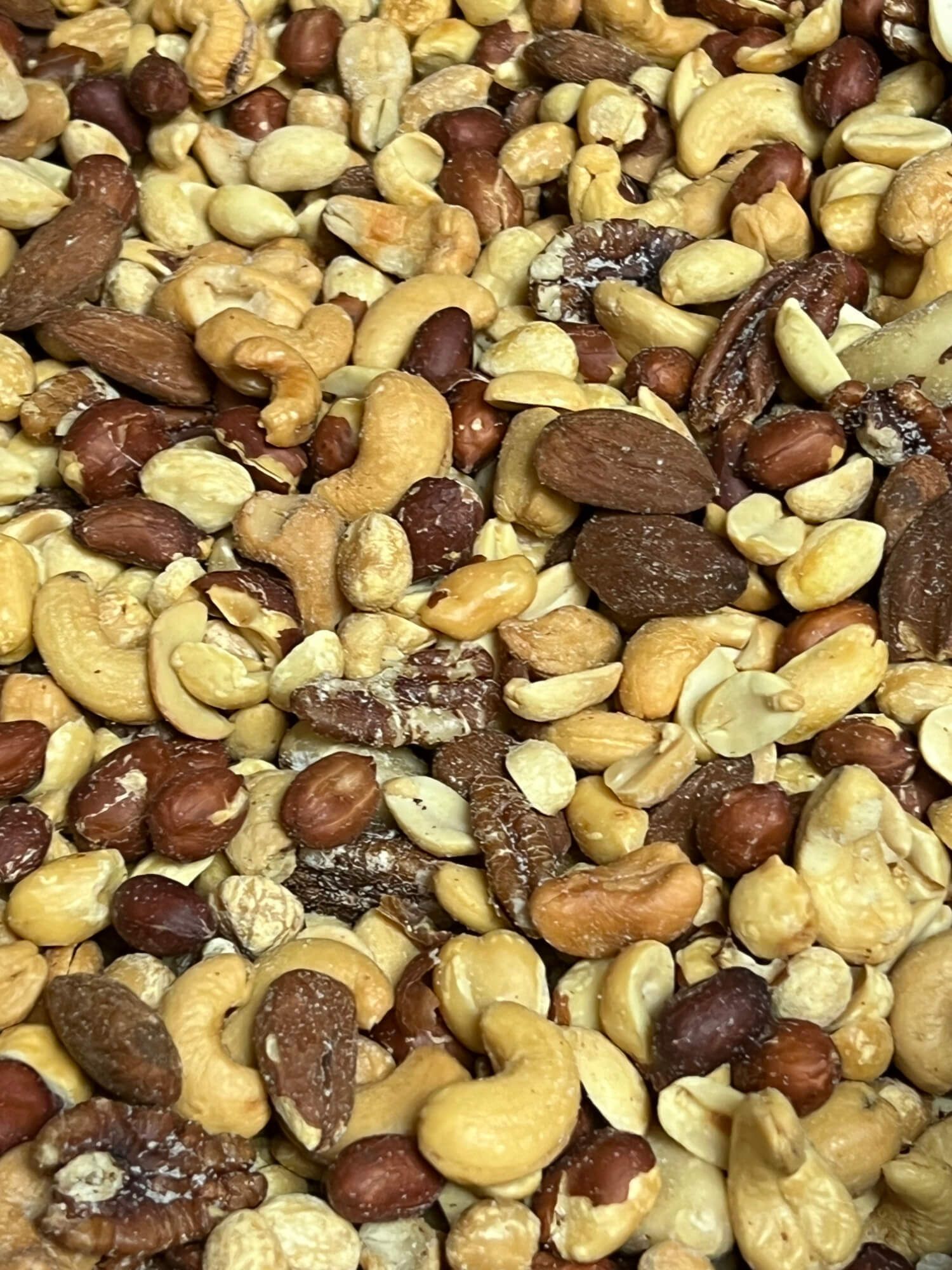 A pile of nuts including peanuts , cashews , and pecans.